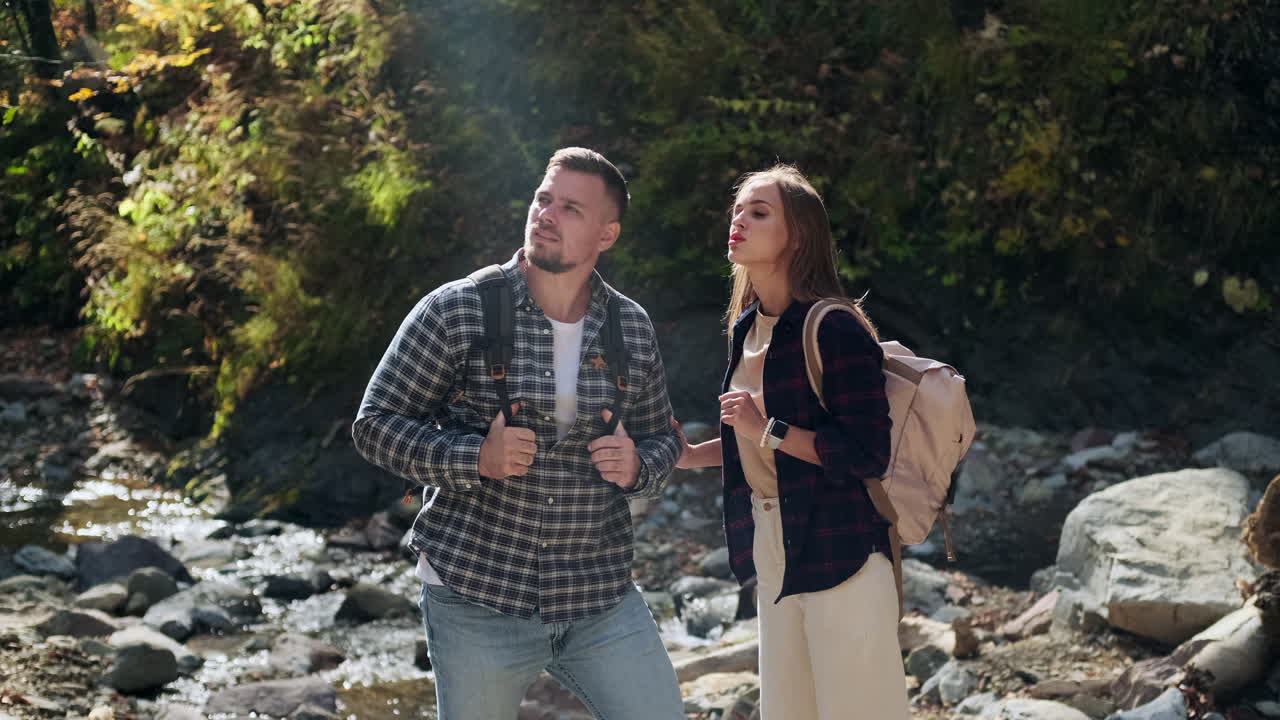 한 커플 이 하천 근처 의 가을 숲 에서 산책 하고 있다