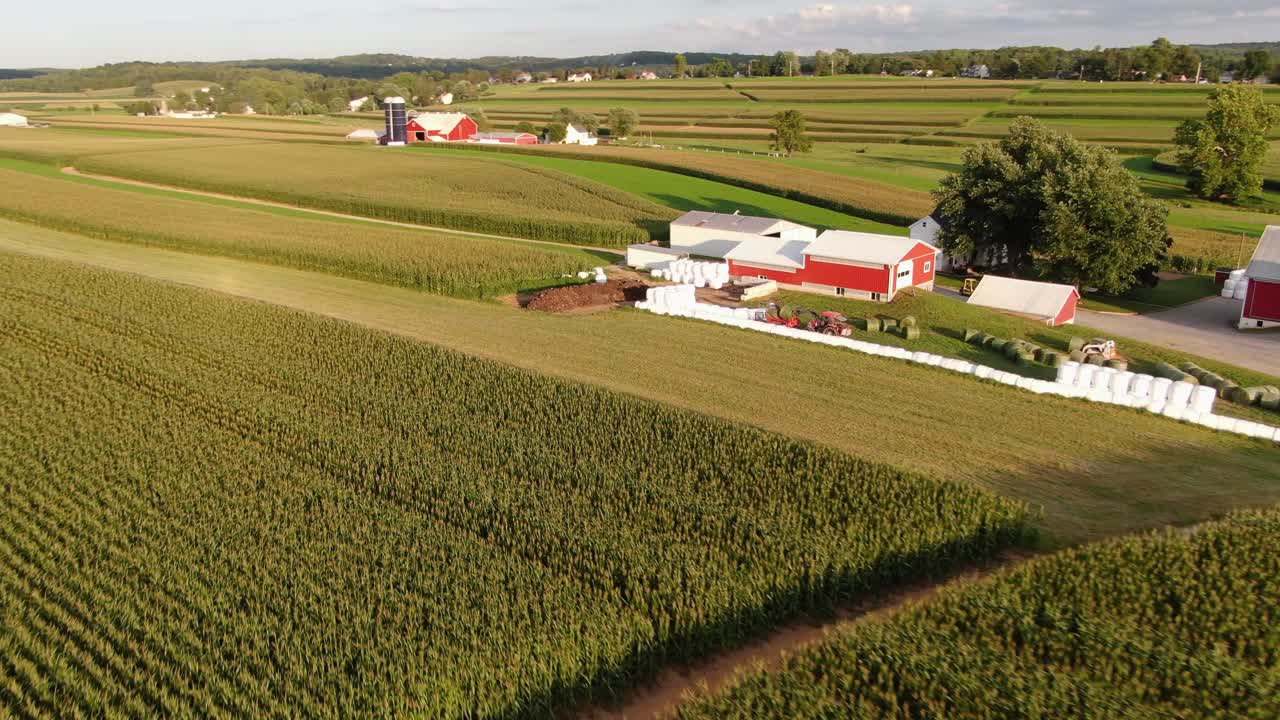 Voo aéreo de aproximação para revelar fardos redondos envoltos em plástico em uma fazenda leiteira familiar na Pensilvânia.