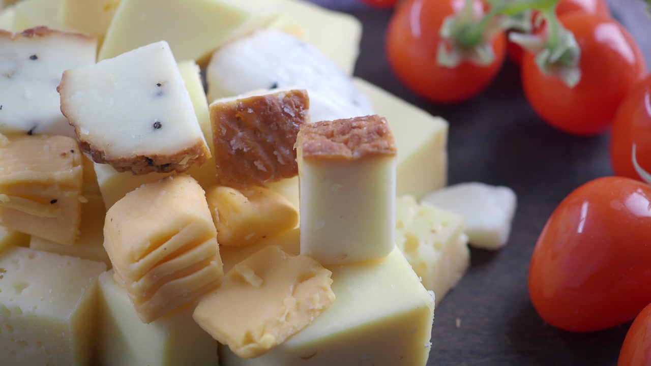 Close-up of Various Cheese Cubes and Slices with Tomatoes