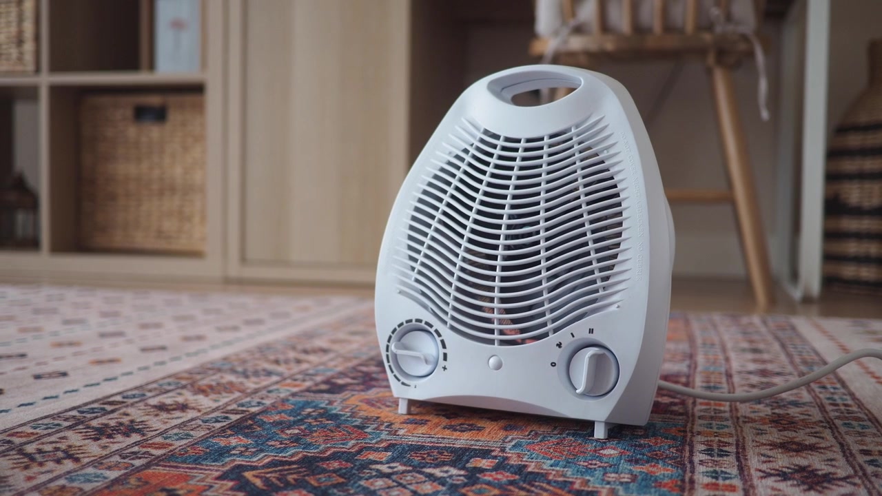 White Electric Fan Heater with Glowing Red Element on a Patterned Rug