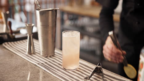 bartender preparing a cocktail with lemon garnish