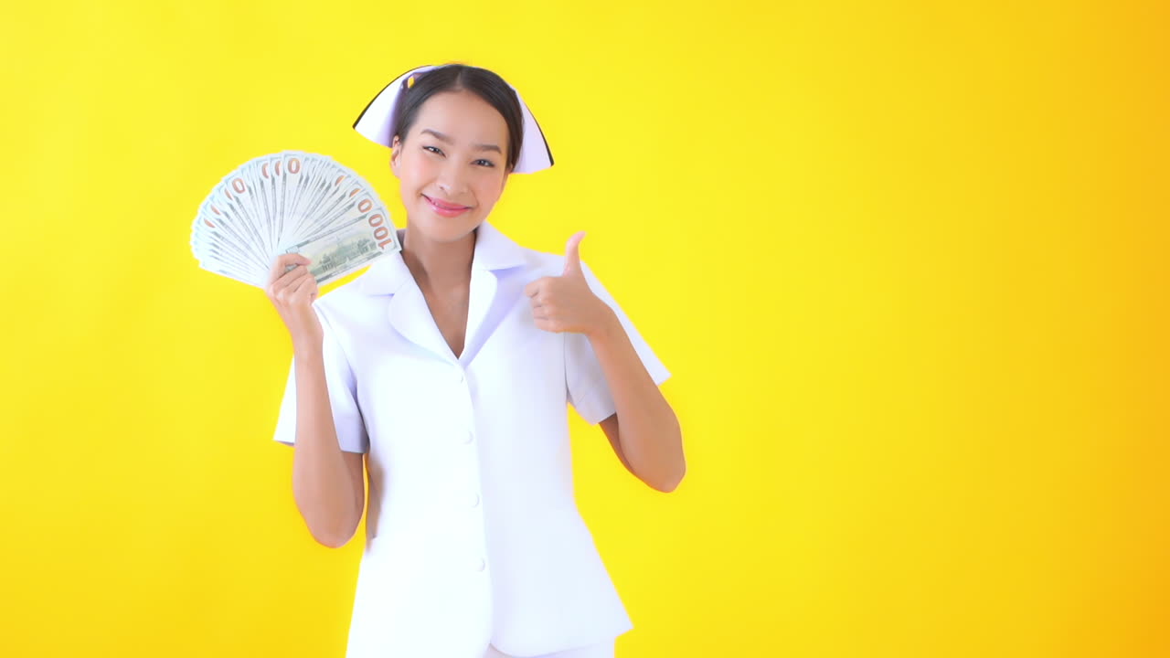 Woman nurse holding a big pile of one hundread dollar notes money in her hands isolated yellow