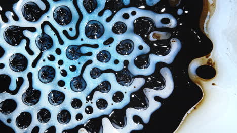 close-up shot of a mesmerizing pattern formed by mixing black and white liquids with blue highlights