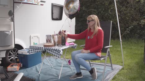 mujer está celebrando su cumpleaños sentada en la mesa de acampada fuera del campista