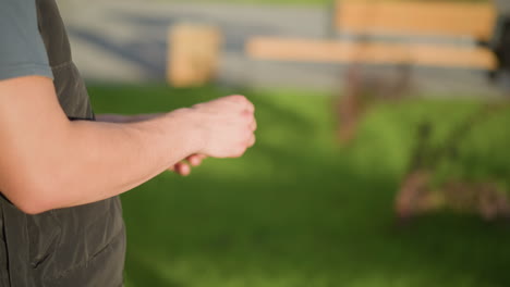 side view of man outdoors breaking cigarette between fingers and throwing it away with blurred background showing green grass, pathway and sunlight casting soft shadows across surfac