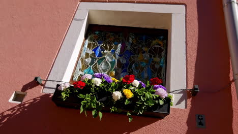 vibrant pink building with stained glass window and colorful flower box