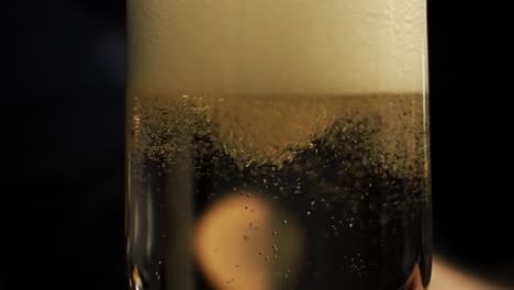 Pouring-sizzling-bubbly-champagne-into-a-glass-releasing-fermentation-and-carbonization---Close-up-slow-motion-shot