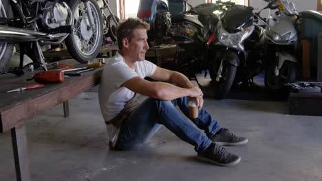 Male-mechanic-drinking-coffee-in-motorbike-repair-garage-4k