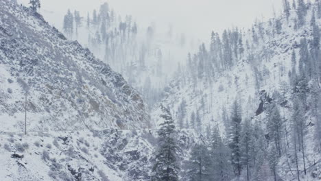 Car-drives-by-on-treacherous-winter-road-in-canyon-with-steep-cliffs