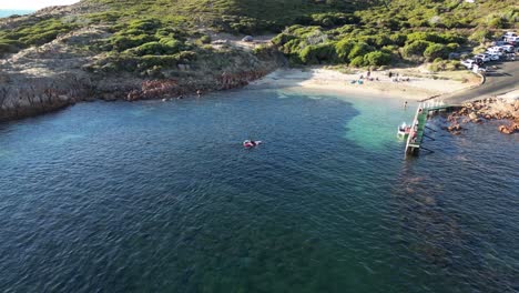 aerial orbiting shot of kayak arriving gracetown beach with sand and resting people in summer - margaret river, western australia