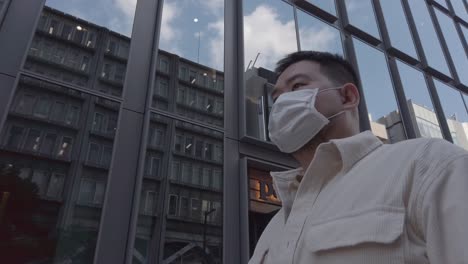 slowmotion asian man walking relaxing in the city of japan among highrise building financial district area in autumn time under clear blue sky, asian tourist business man in 60p video