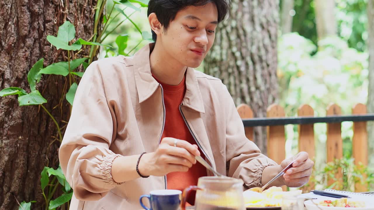 Young asian man enjoying delicious noodles at cafe outdoor