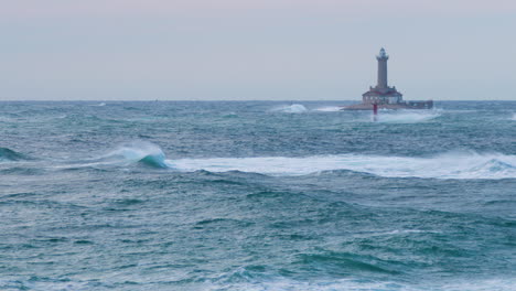 Faro-Porer-En-Tiempo-Tormentoso,-Grandes-Olas-Haciendo-Crestas,-Somormujos-Volando-A-Través-Del-Mar-Inquieto