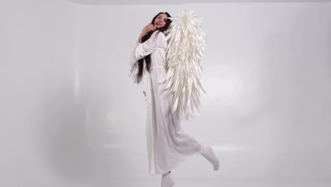 beautiful brunette woman with white wings on a white background beautiful brunette woman with white wings on a white background girl in an angel costume high quality video
