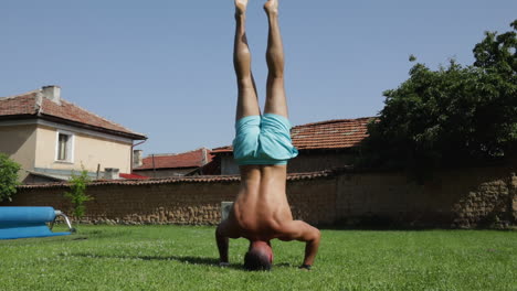 fit male model performing a handstand outdoors by a backyard swimming pool