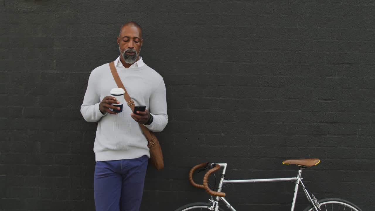 African American man drinking a coffee and using his phone