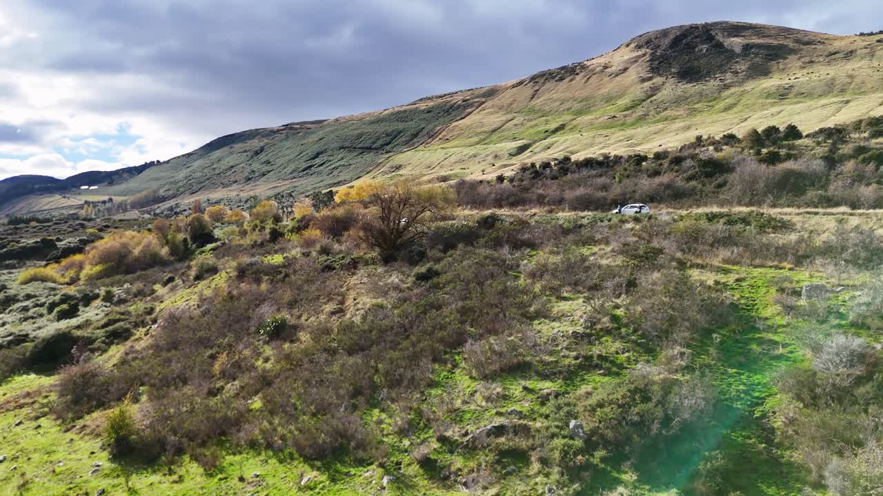 A serene view of lush green hills and mountains under a cloudy sky in Queenstown, New Zealand. Captured with natural lighting