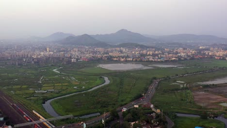 área suburbana de vasai con edificios, estación de tren, carreteras y naturaleza panorámica en la india - panorámica aérea