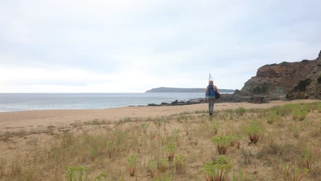 a man walking along a beautiful coastline with spear fishing gear in australia