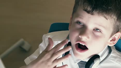 cu slow motion schoolboy sits at table in school uniform and yawns while doing his homework