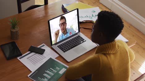 African-american-woman-using-laptop-on-video-call-with-male-colleague-working-from-home