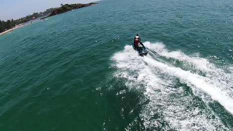 aerial dolly in of skilled man riding a jet sky in turquoise sea at daytime near the coast of mirissa beach, sri lanka