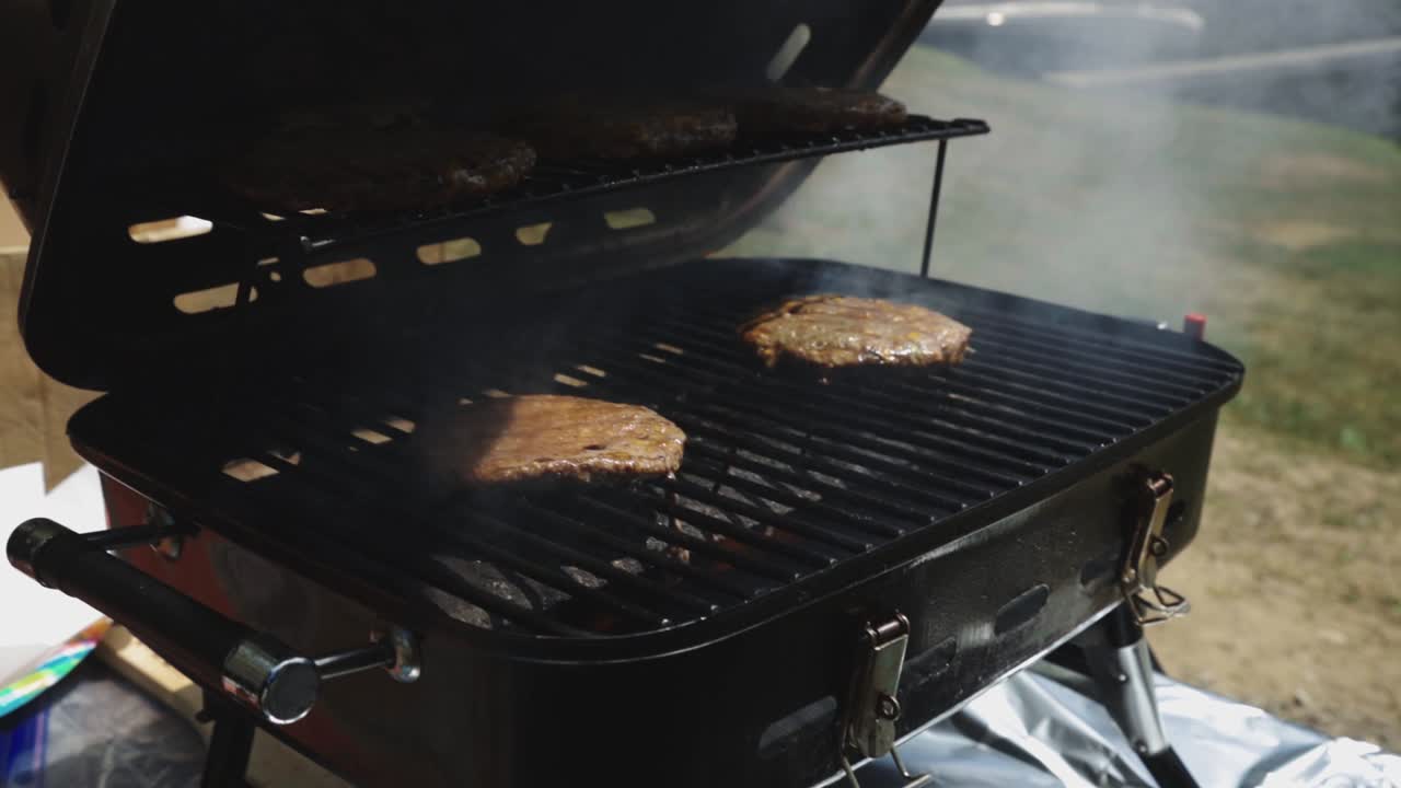 Hand Of A Man Opening A Griller With Grilled Beef Patties