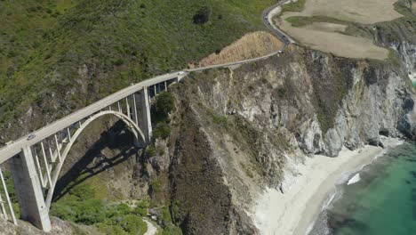 aerial view above bixby creek bridge with beach and pacific ocean below