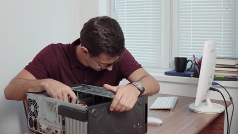 Young-professional-worker-trying-to-repair-a-computer-in-the-office-using-a-screwdriver-and-upgrading-computer-hardware.-Shot-in-4k