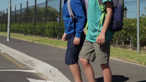 dos niños con bolsas escolares buscando tráfico mientras cruzan la carretera