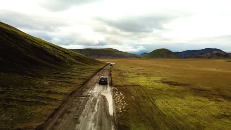 aerial landscape view over four wheel drive cars traveling on a dirt road through icelandic highlands