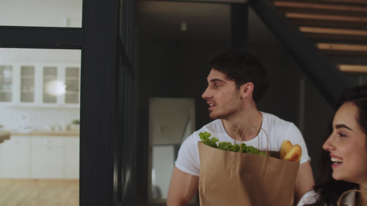 retrato de una pareja feliz sosteniendo paquetes en casa. familia caminando con una bolsa de papel