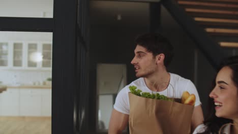 retrato de una pareja feliz sosteniendo paquetes en casa. familia caminando con una bolsa de papel