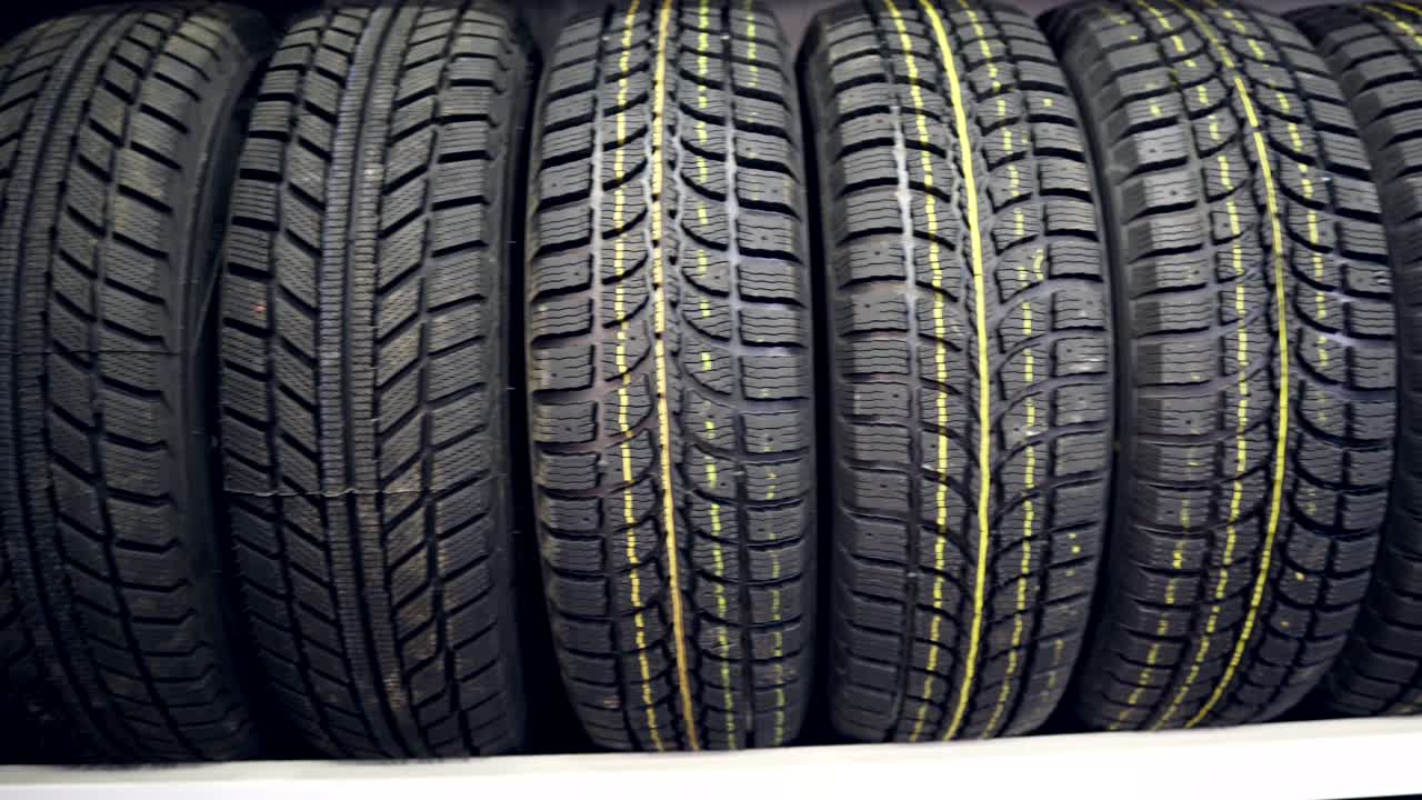 muchos neumáticos de invierno nuevos en los estantes y en las columnas. panorama de la tienda.