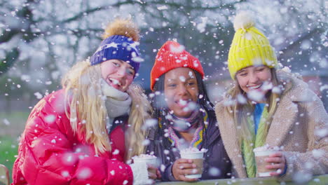 portrait of teenage girls enjoying hot chocolate on snowy winter walk in countryside together