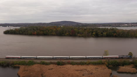 A-drone-shot-over-a-marsh,-surrounded-by-the-fall-foliage-on-a-cloudy-day,-in-upstate-NY