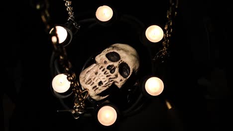 dummy human skull surrounded by candles on chains