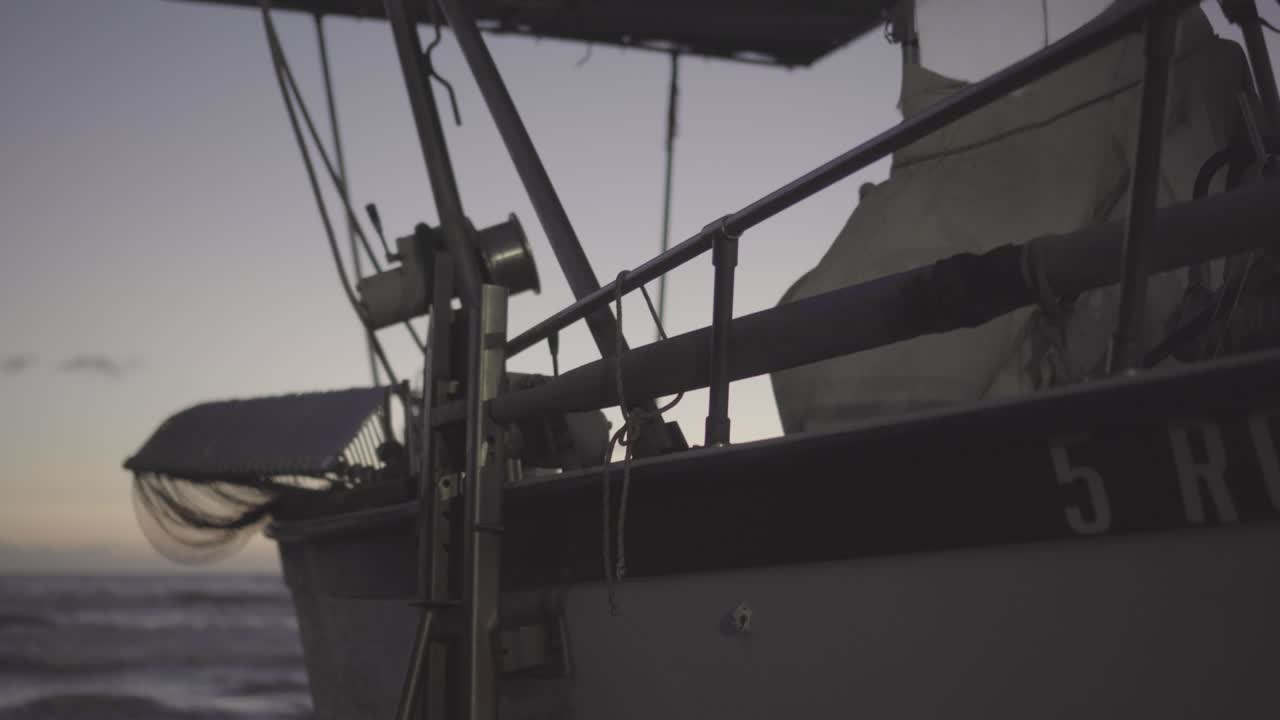 Una barca da pesca parcheggiata sulla riva con le onde del mare sullo sfondo durante l'ora blu - Ripresa dall'alto verso il basso.