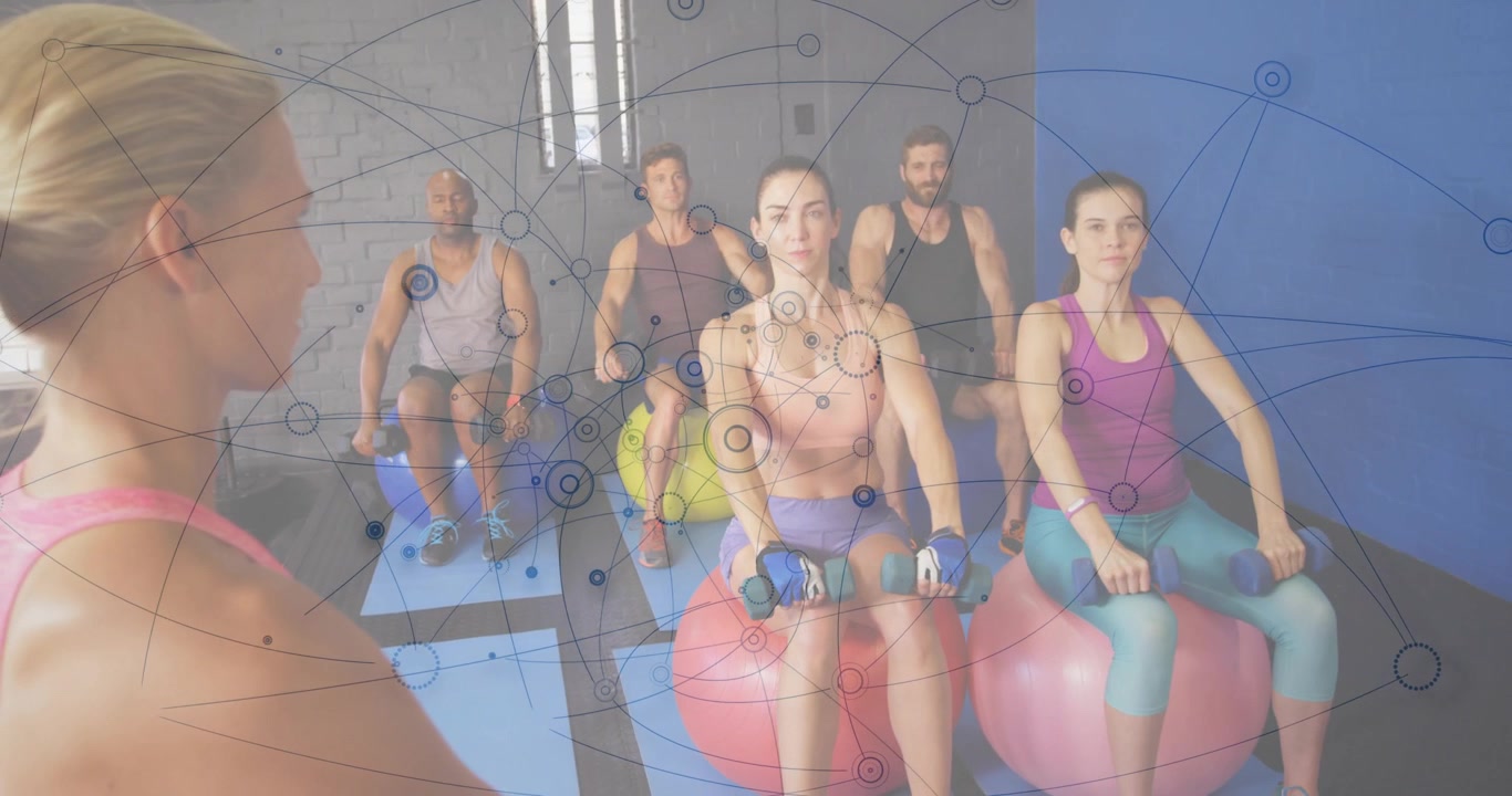 Trenér dává pokyny skupině zvedající činky na balančních míčích, zatímco se rozšiřuje síťový překryv pro fitness.
