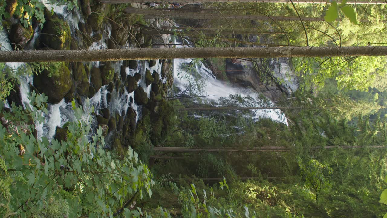 sensacional toma vertical de una cascada austriaca con un pequeño arroyo en el bosque
