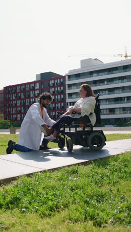 Doctor examining patient in wheelchair outdoors