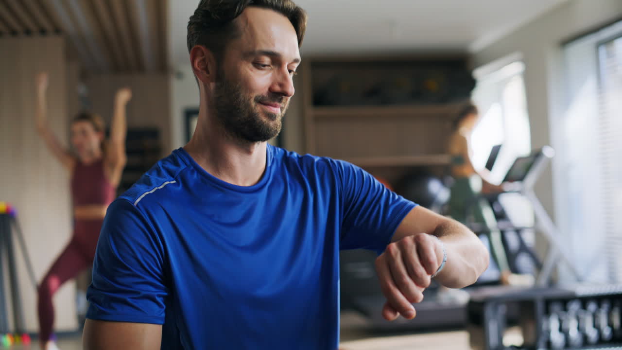 Primo piano di un atleta sorridente che guarda lo smartwatch in palestra. Ritratto di un uomo felice