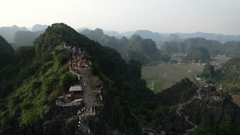 los turistas suben las empinadas escaleras de la cima de la montaña para visitar la estatua del dragón acostado en el mirador de la cueva mua en ninh binh vietnam