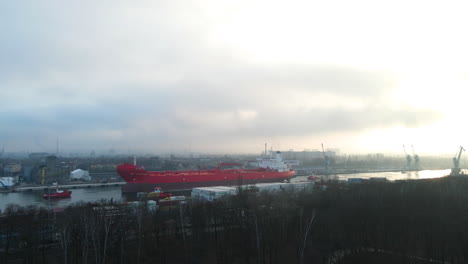 Petroleum-Tanker-Pulled-By-Tugboats-Crossing-River-Within-Nowy-Port-At-Sunrise-In-Westerplatte,-Poland