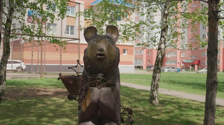 Scultura di orso in legno che tiene un pesce in un parco residenziale.