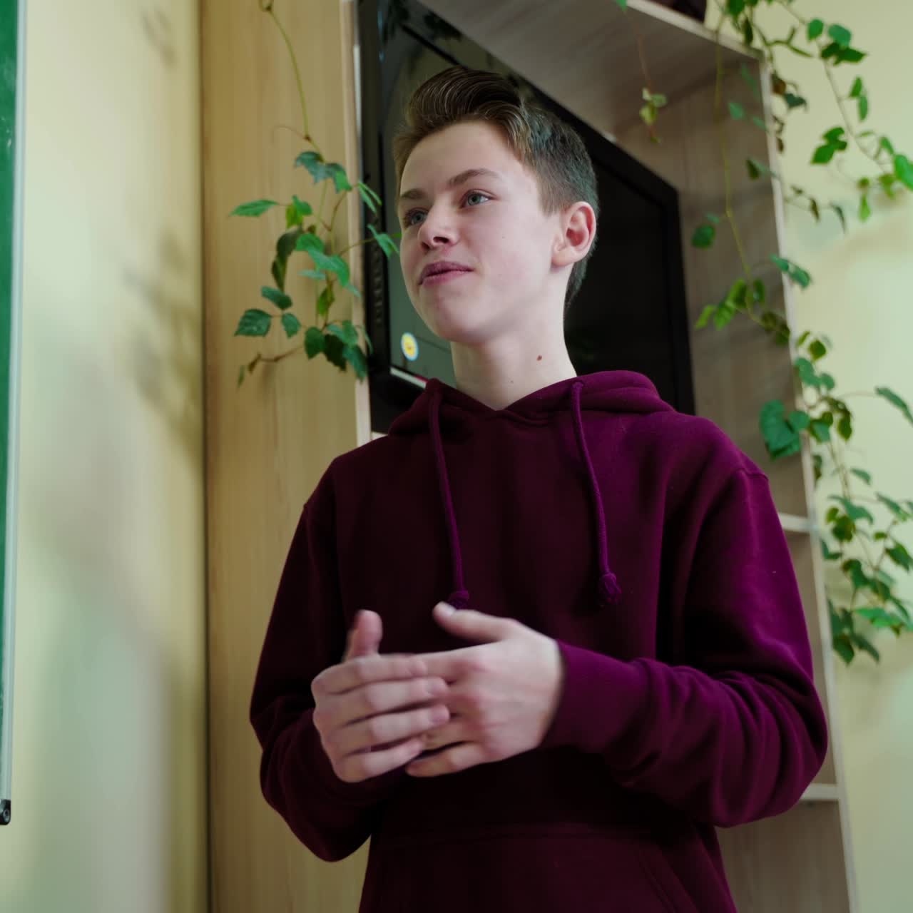 Schoolboy answering the teacher. Clever teen student standing near the blackboard in the classroom and talking. Education at school.