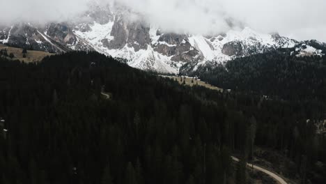Drone-shot-pulling-away-from-a-forest-to-reveal-the-Dolomites-mountains-in-Italy