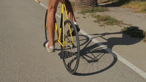 person riding a yellow fixed gear bicycle on a road