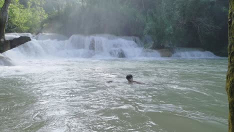 Person swimming in a natural waterfall