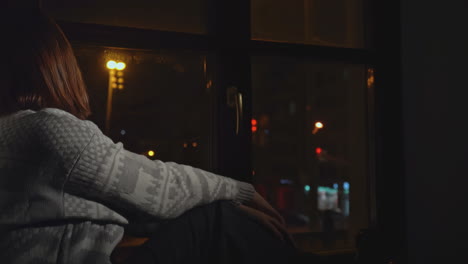 woman sitting by window at night